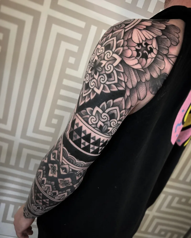 Ornamental flowers arm sleeve tattoo done by Jack Peppiette