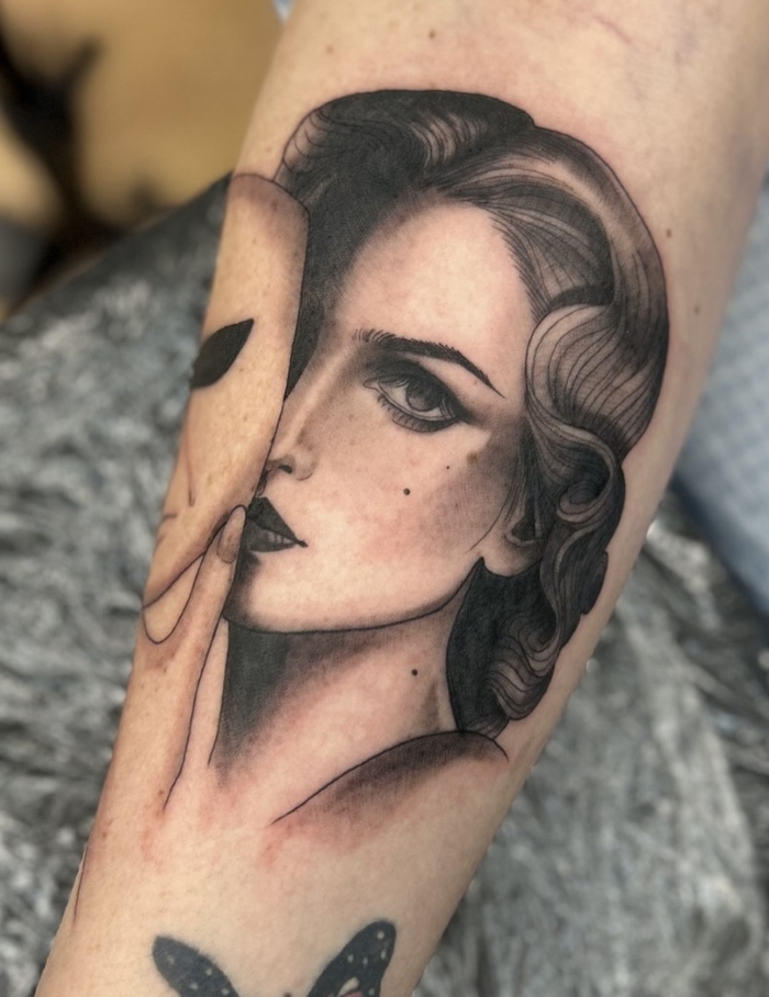 a tattoo of a woman with a mask on her arm